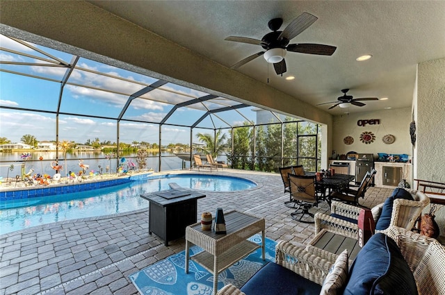 view of swimming pool featuring a water view, an outdoor kitchen, a lanai, and a patio