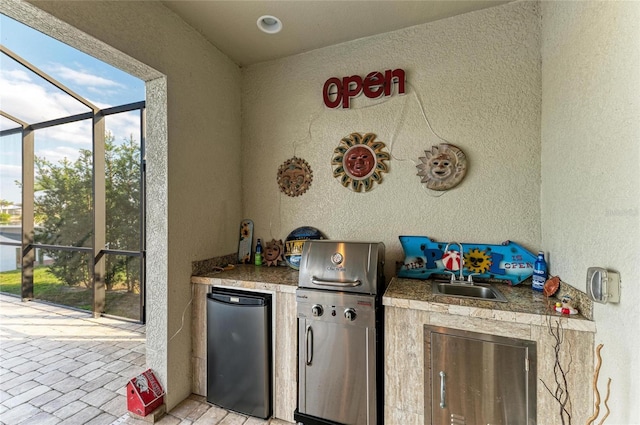 view of patio with exterior kitchen, a grill, a lanai, and sink