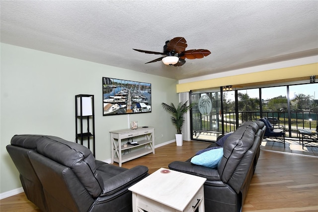 living room with dark hardwood / wood-style flooring, ceiling fan, and a textured ceiling