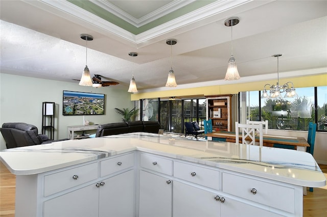 kitchen with a kitchen island, white cabinetry, hanging light fixtures, ornamental molding, and light hardwood / wood-style floors