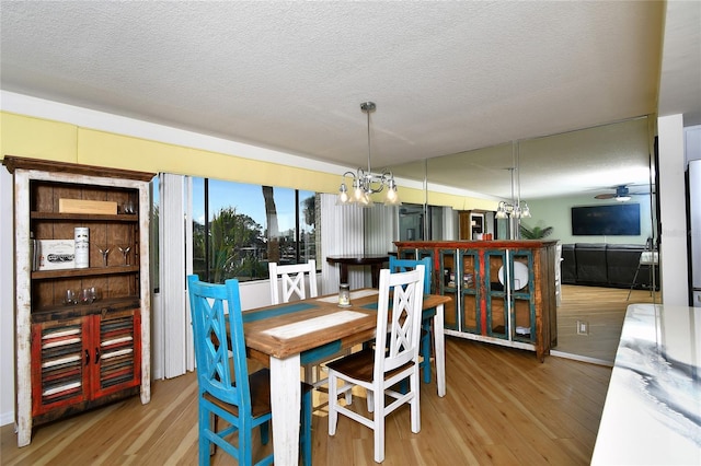 dining room with a notable chandelier, light hardwood / wood-style floors, and a textured ceiling