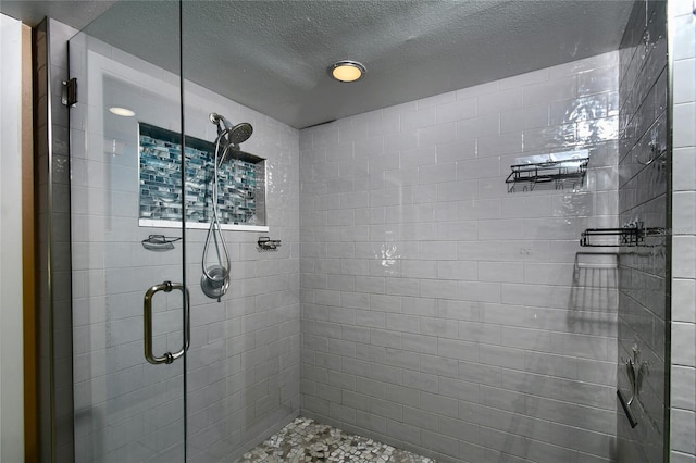 bathroom featuring a shower with shower door and a textured ceiling