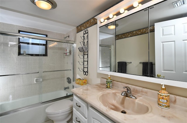 full bathroom with enclosed tub / shower combo, vanity, and toilet