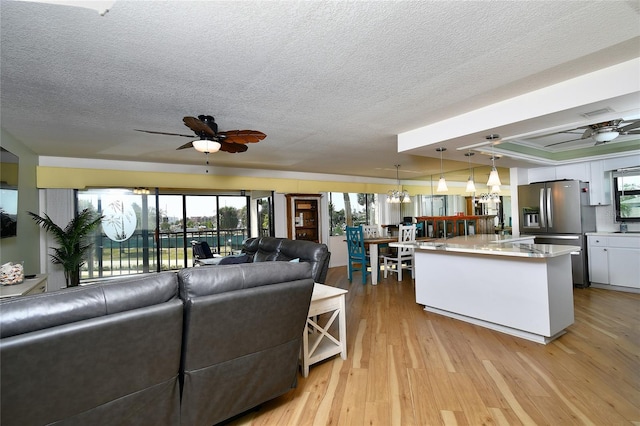 living room featuring ceiling fan, light hardwood / wood-style floors, and a textured ceiling