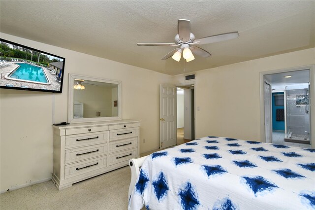 bedroom with ceiling fan, connected bathroom, light colored carpet, and a textured ceiling