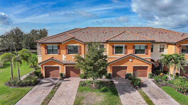 mediterranean / spanish home featuring a garage and a front lawn