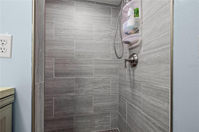 bathroom featuring a tile shower and vanity