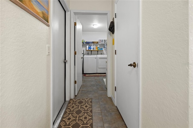 corridor with dark tile patterned floors and washing machine and dryer