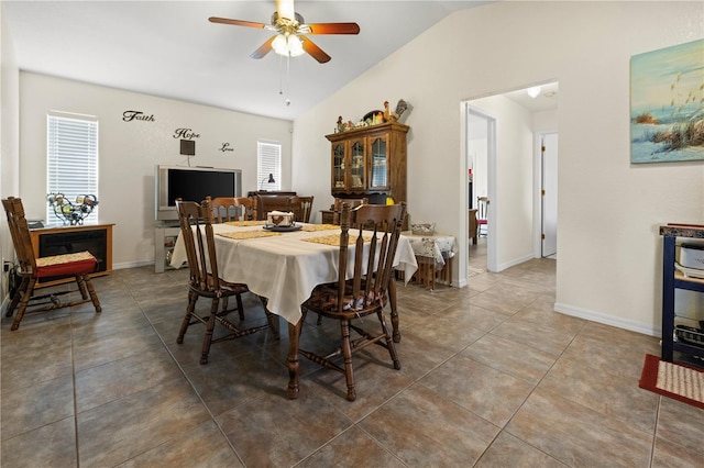 dining space featuring ceiling fan, tile patterned flooring, and vaulted ceiling