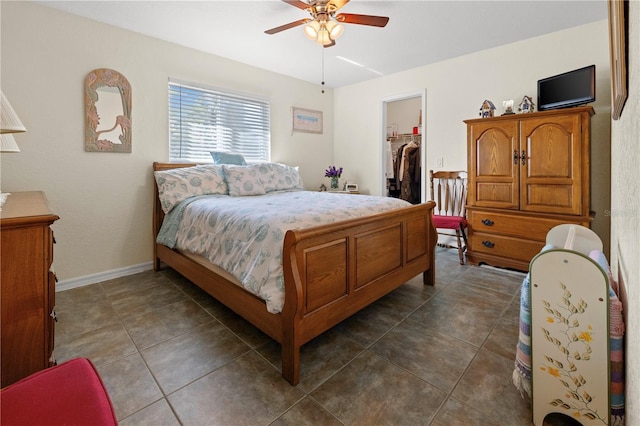 bedroom featuring dark tile patterned floors, a walk in closet, ceiling fan, and a closet