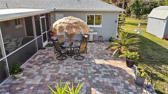 view of patio / terrace with grilling area, fence, outdoor dining area, a sunroom, and an outbuilding