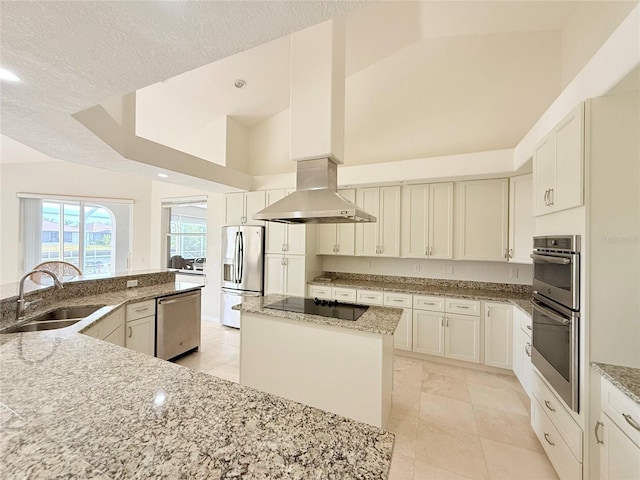 kitchen featuring sink, stainless steel appliances, light stone counters, island range hood, and an island with sink