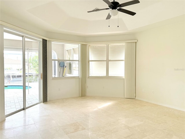 empty room featuring ceiling fan and a tray ceiling