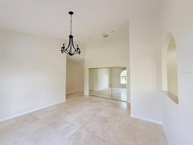 empty room featuring a notable chandelier and a high ceiling