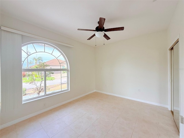 tiled spare room featuring ceiling fan