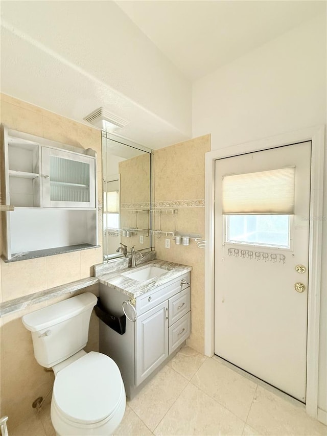 bathroom with tile walls, vanity, tile patterned flooring, and toilet