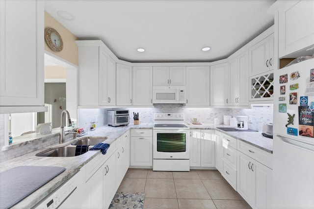 kitchen featuring sink, white appliances, light tile patterned floors, white cabinetry, and light stone countertops