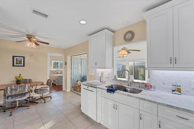 kitchen with sink, light tile patterned floors, dishwasher, white cabinetry, and tasteful backsplash