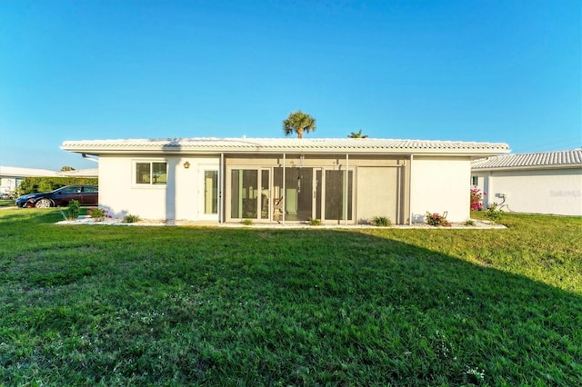 back of property featuring a sunroom and a lawn