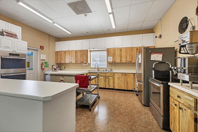 kitchen with sink, white cabinetry, backsplash, stainless steel appliances, and a center island