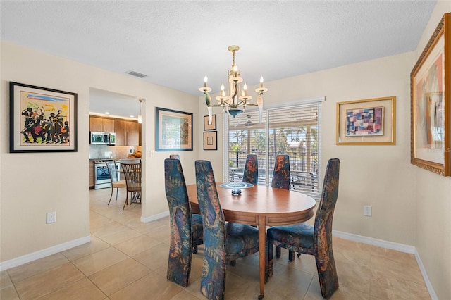 tiled dining room featuring a textured ceiling and a chandelier