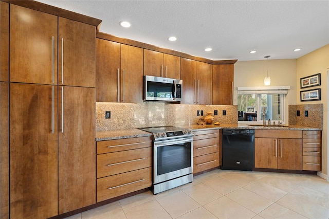 kitchen with sink, appliances with stainless steel finishes, hanging light fixtures, light stone counters, and decorative backsplash