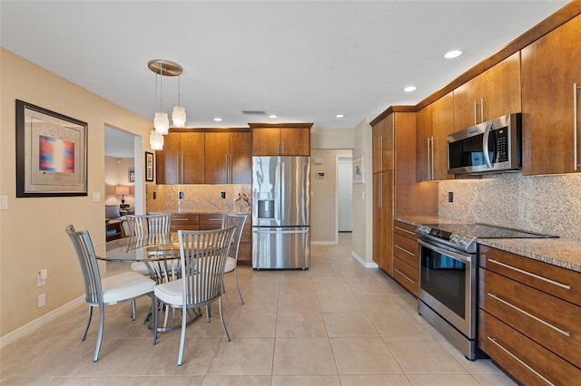 kitchen featuring pendant lighting, appliances with stainless steel finishes, light stone counters, light tile patterned flooring, and decorative backsplash