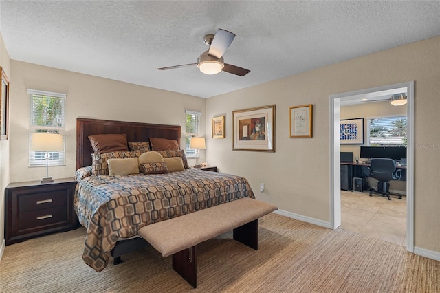 carpeted bedroom featuring ceiling fan and a textured ceiling