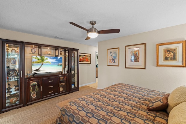 bedroom with ceiling fan, light colored carpet, and a textured ceiling