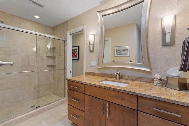 bathroom featuring vanity, a shower with shower door, and tile patterned floors