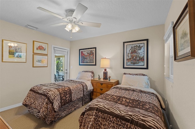 carpeted bedroom featuring ceiling fan and a textured ceiling