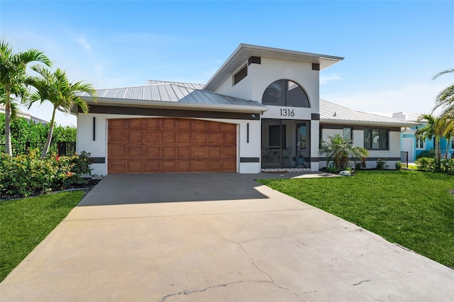 view of front facade with driveway, metal roof, an attached garage, a standing seam roof, and stucco siding