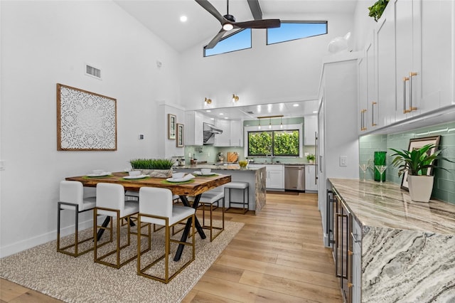 dining area with visible vents, a ceiling fan, beamed ceiling, light wood-type flooring, and high vaulted ceiling