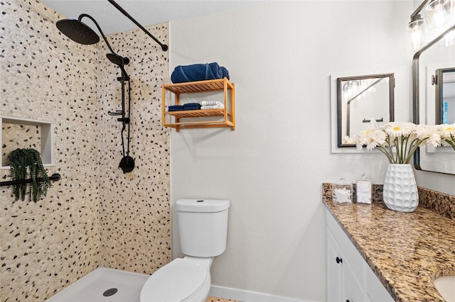 full bathroom featuring vanity, a tile shower, and toilet