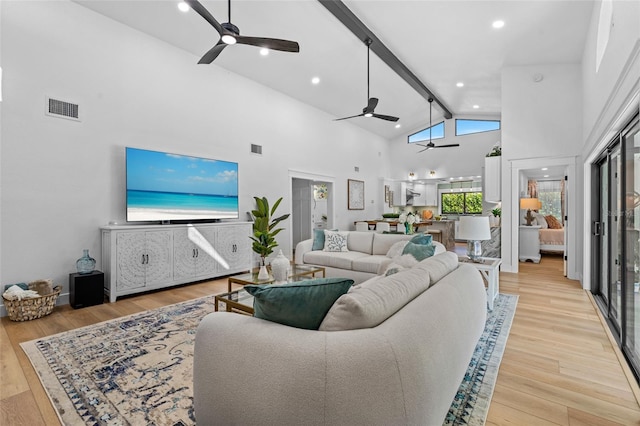 living room with beam ceiling, light wood finished floors, visible vents, a ceiling fan, and high vaulted ceiling