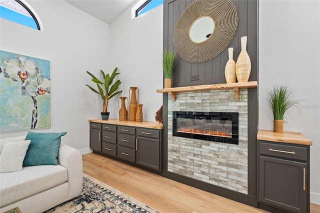 living area featuring a wealth of natural light, vaulted ceiling, a fireplace, and light wood finished floors