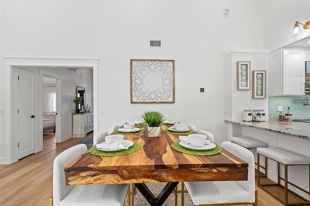 dining space featuring a bar, light wood-style flooring, and visible vents