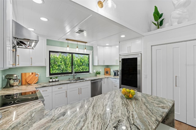 kitchen with extractor fan, visible vents, white cabinets, appliances with stainless steel finishes, and light stone countertops