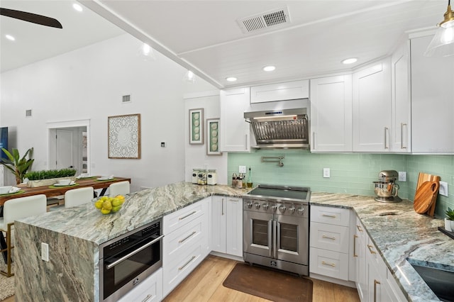 kitchen with visible vents, stainless steel appliances, a peninsula, and white cabinetry