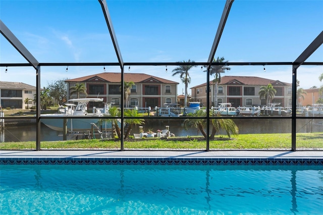 view of pool featuring glass enclosure, a yard, a water view, and a residential view