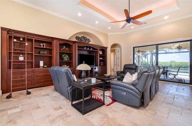 living room featuring ornamental molding, ceiling fan, and a tray ceiling