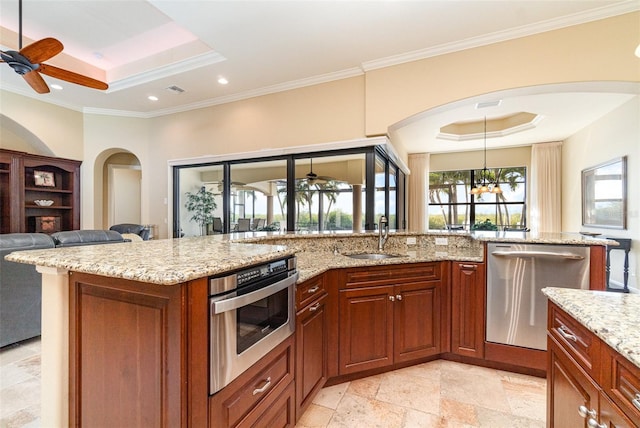 kitchen with light stone counters, sink, a tray ceiling, and stainless steel appliances