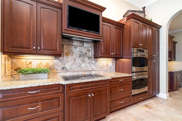 kitchen featuring tasteful backsplash, ornamental molding, stainless steel double oven, light stone countertops, and black stovetop