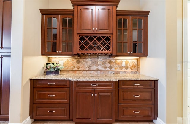 bar featuring light stone counters and tasteful backsplash