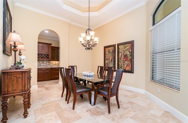 dining area featuring a tray ceiling, a notable chandelier, and crown molding