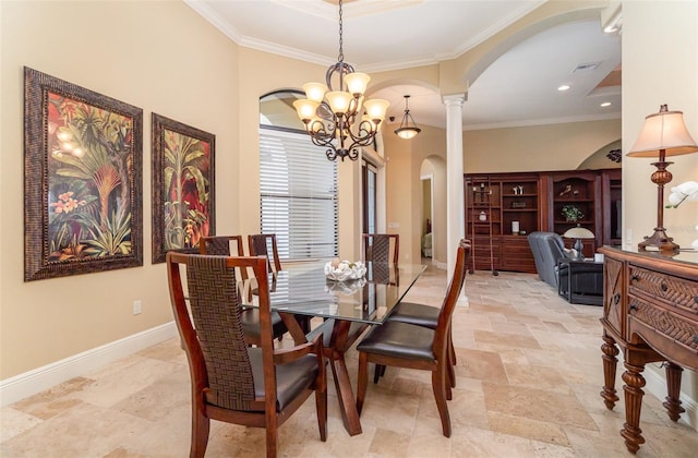 dining space featuring crown molding, a notable chandelier, and ornate columns