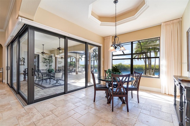 dining room with a water view, a raised ceiling, a chandelier, and a wealth of natural light