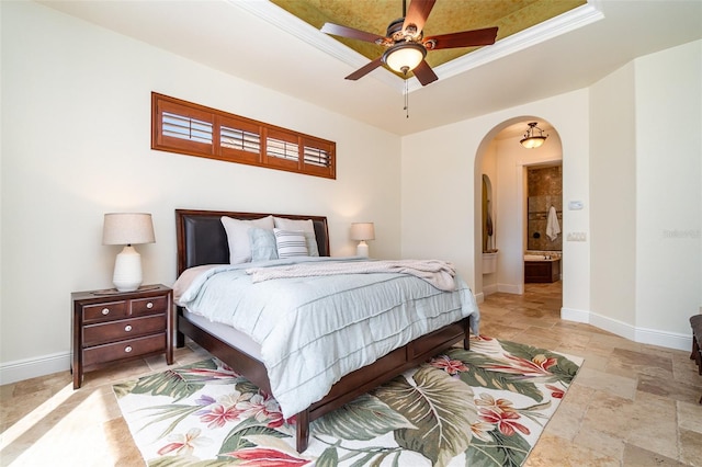 bedroom with ceiling fan, ensuite bathroom, and a tray ceiling