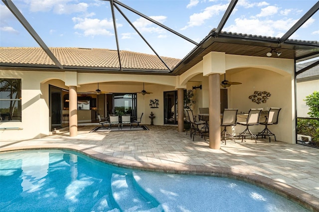 back of property with glass enclosure, ceiling fan, and a patio area