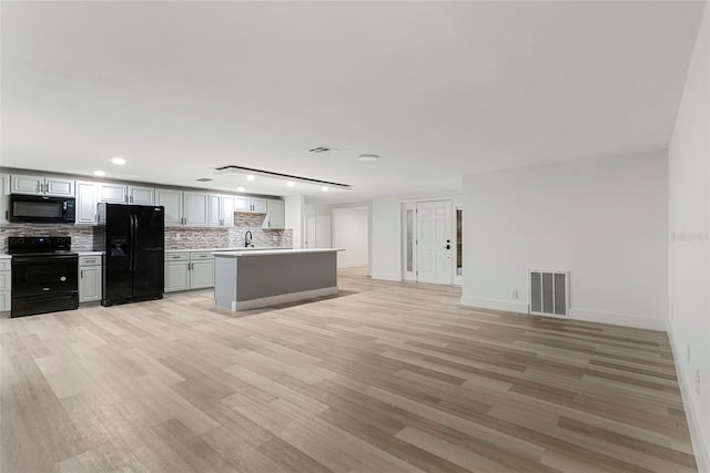 kitchen with sink, light hardwood / wood-style flooring, backsplash, a center island, and black appliances